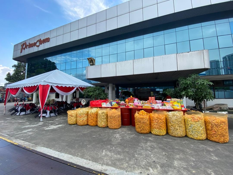 Wide exterior view of the PrimeChem building with an extensive display of offerings and sacks of joss paper.