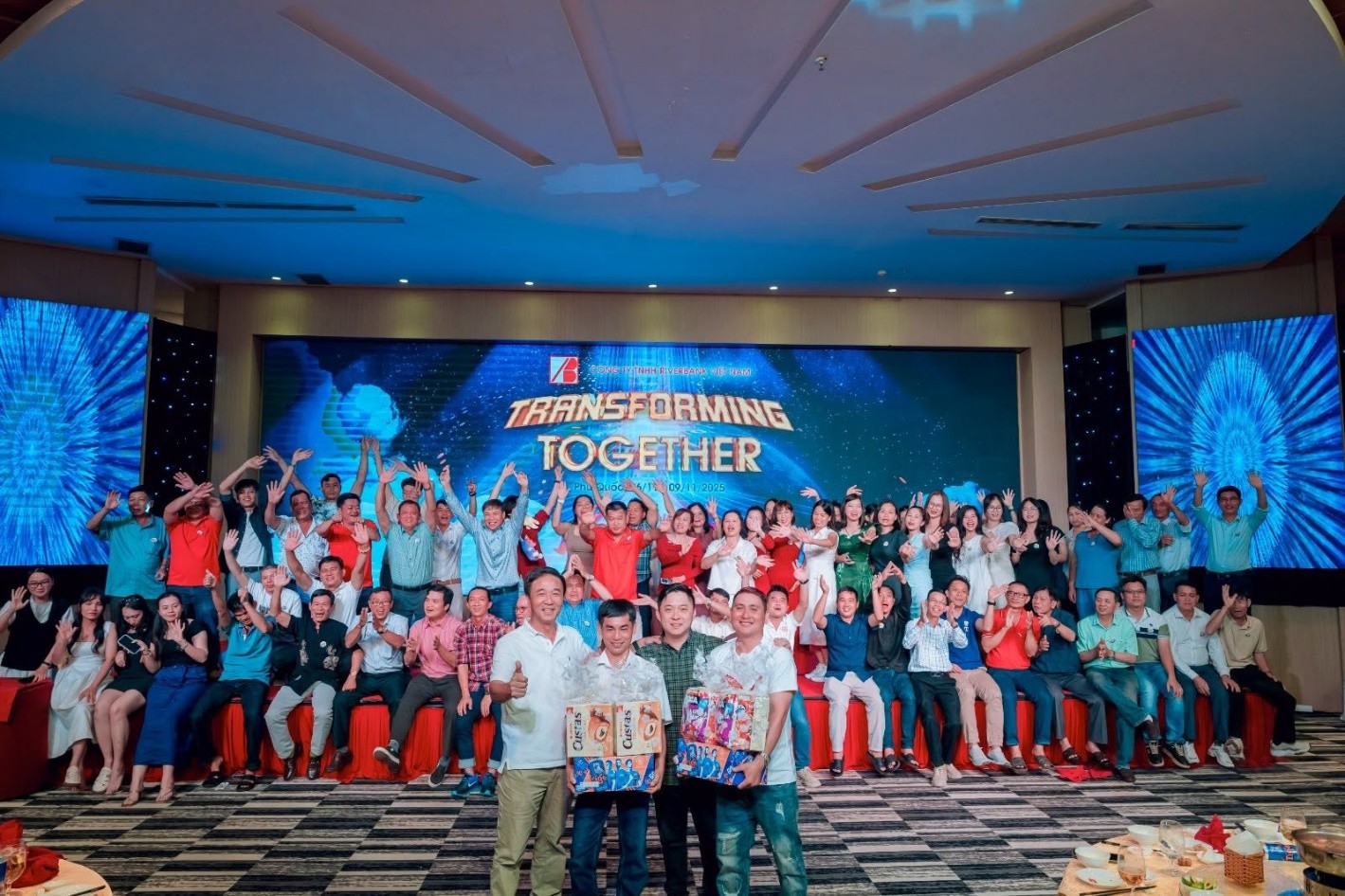 Employees gathered on stage during the gala dinner celebration with a large "Transforming Together" screen backdrop.