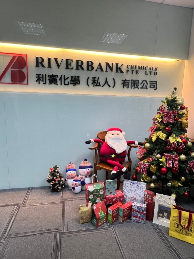 Office reception area decorated with a Christmas tree, seated Santa doll, and wrapped gift boxes underneath.
