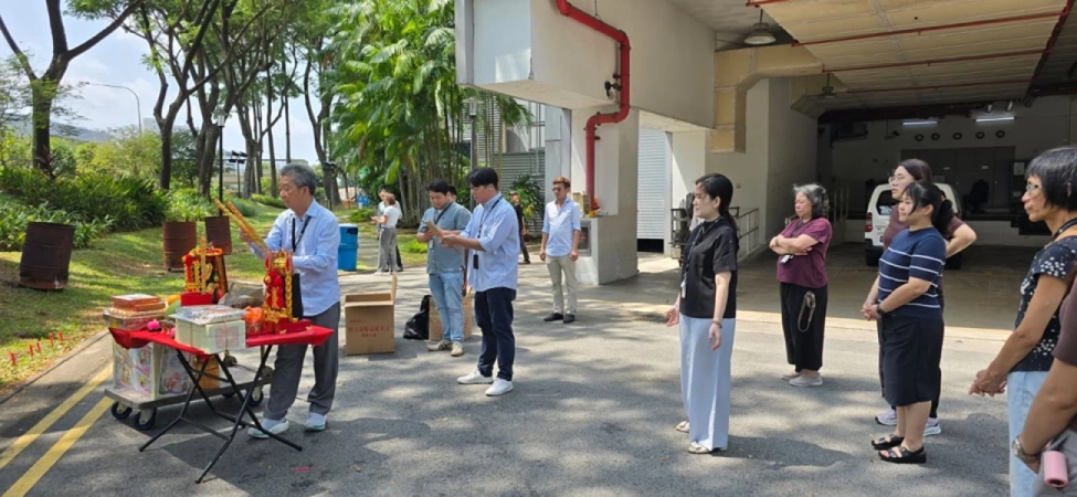 Employees participating in a prayer ceremony with offerings laid out on a table outdoors at PrimeChem.