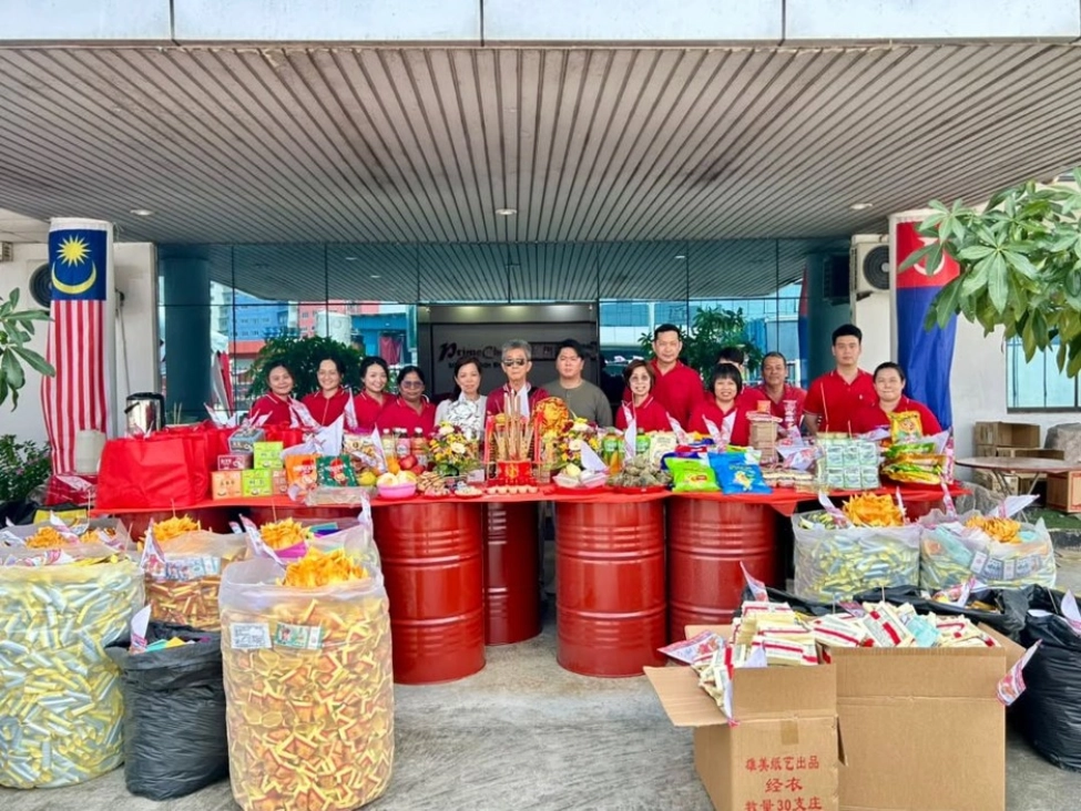 Large group of employees posing behind a long table filled with festival offerings and red drums at PrimeChem.