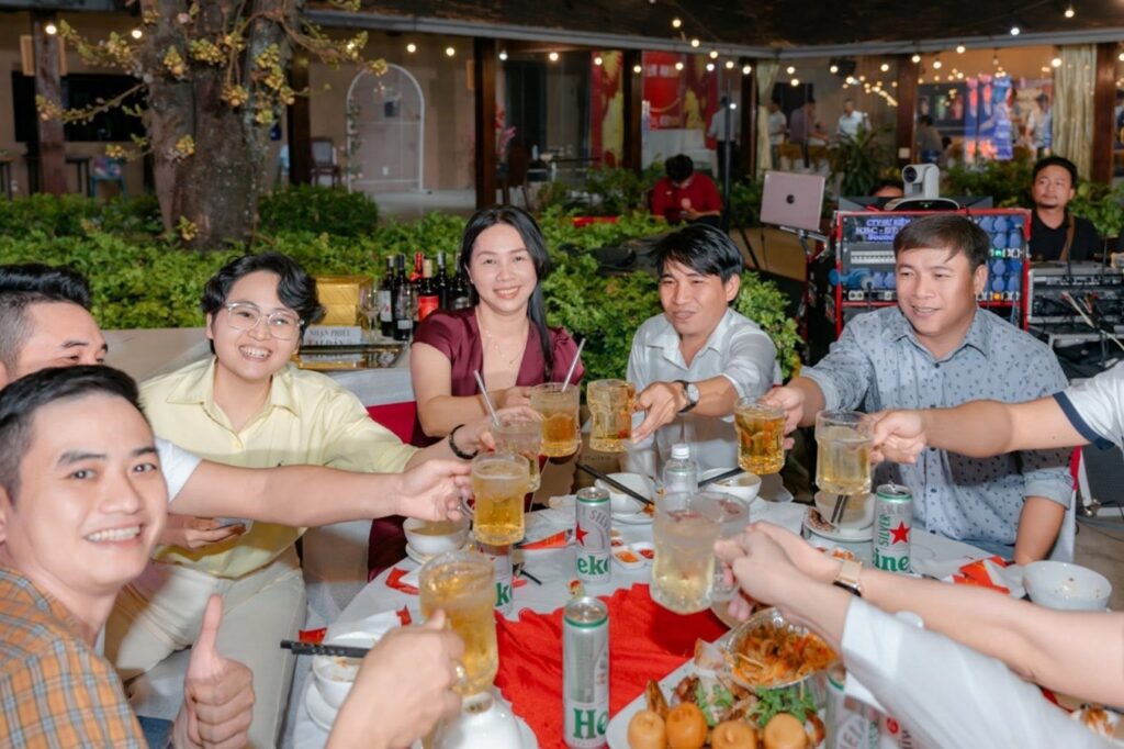 A group of colleagues smiling and raising their glasses for a celebratory toast at a round banquet table.