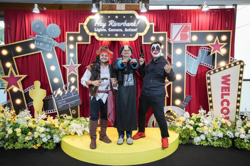 Three staff members posing in pirate, traditional Taoist priest, and clown costumes.