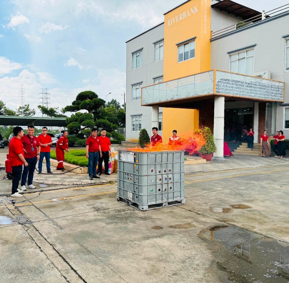 Employees gathered outdoors near a large metal container burning joss paper at Riverbank Vietnam.